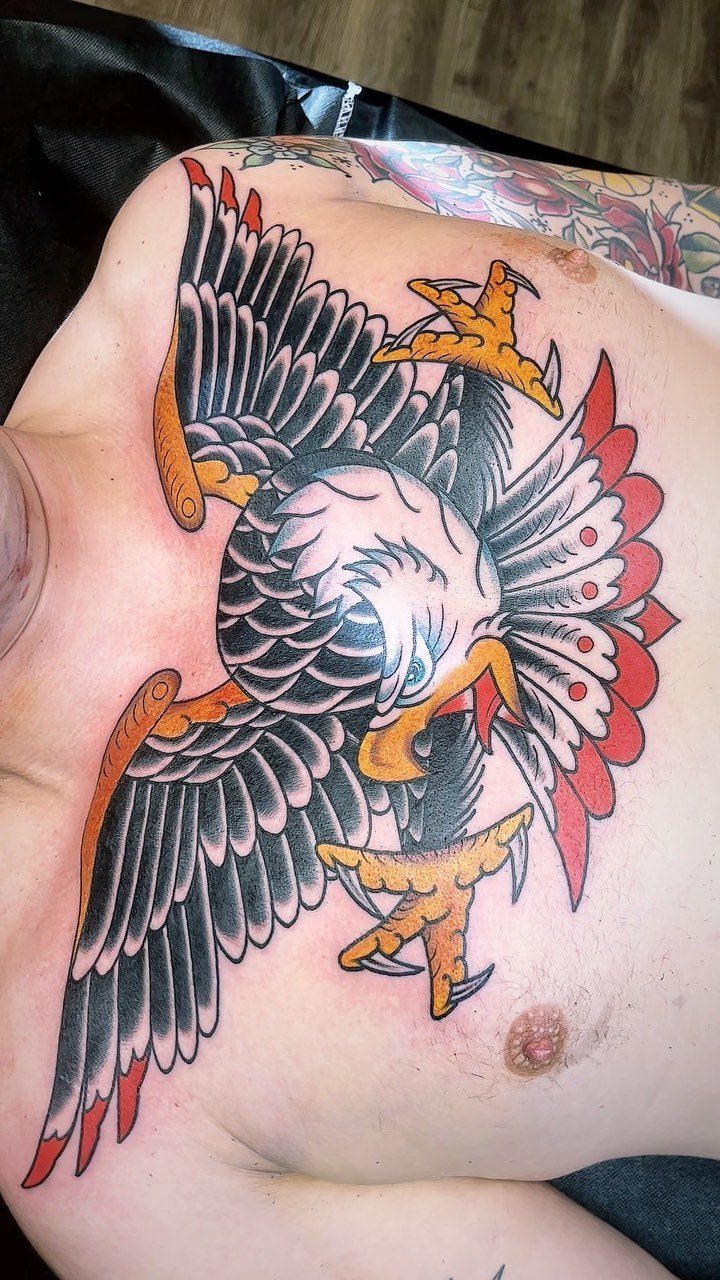 An American traditional eagle tattoo with spread wings on a person's chest.