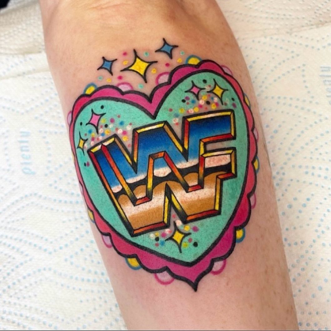 A colorful heart-shaped tattoo with a 3D logo on a person's arm.