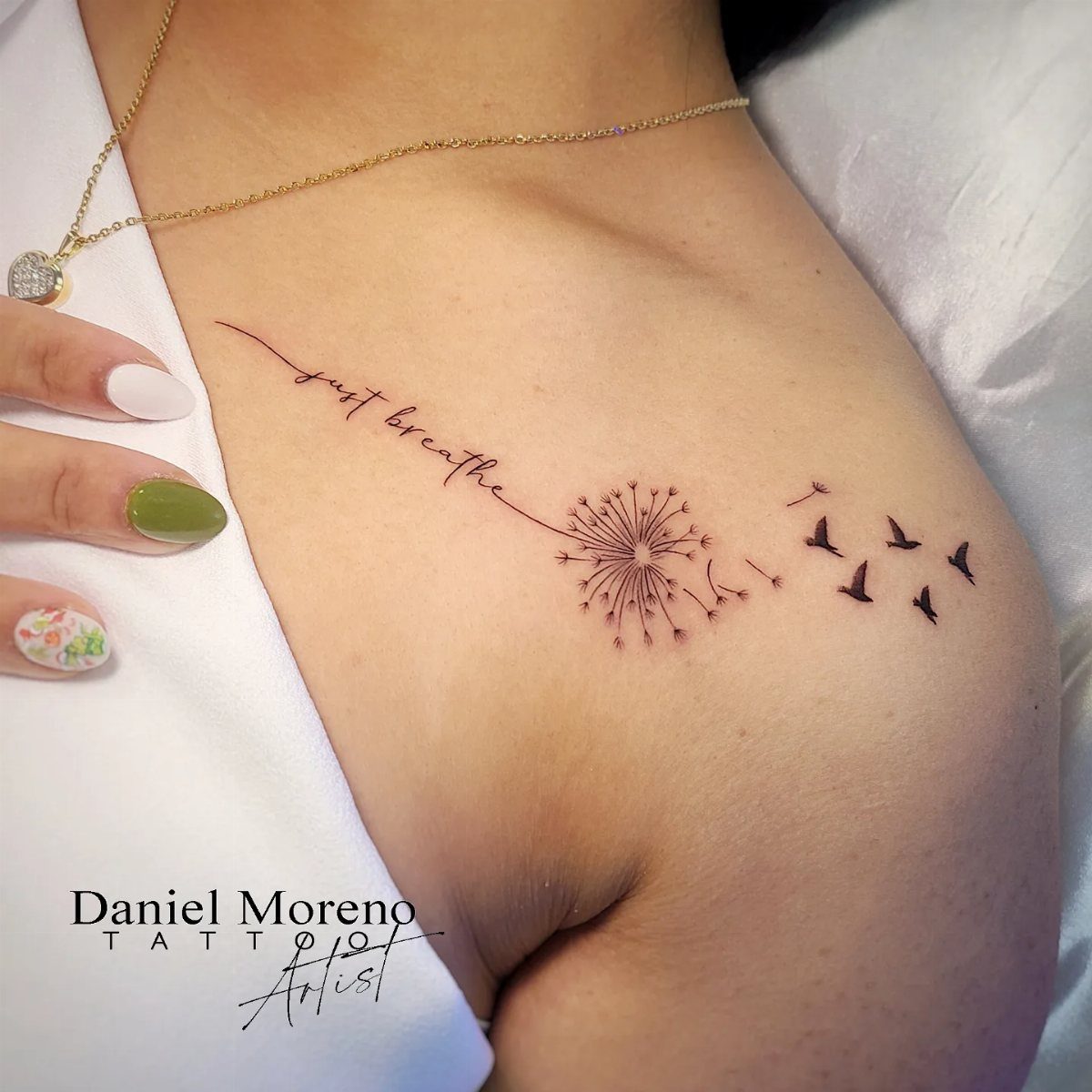 A fine line tattoo of a dandelion and birds flying away on a collarbone.