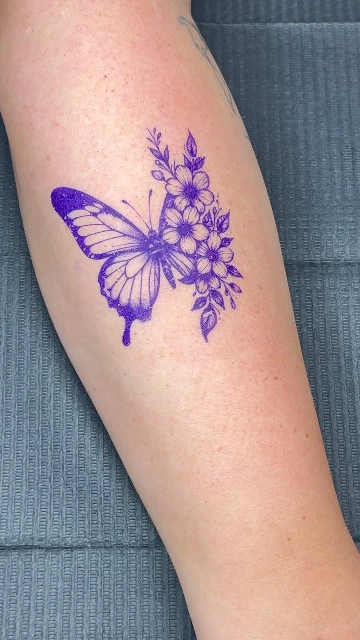 A purple butterfly tattoo design with flowers on a person's arm.