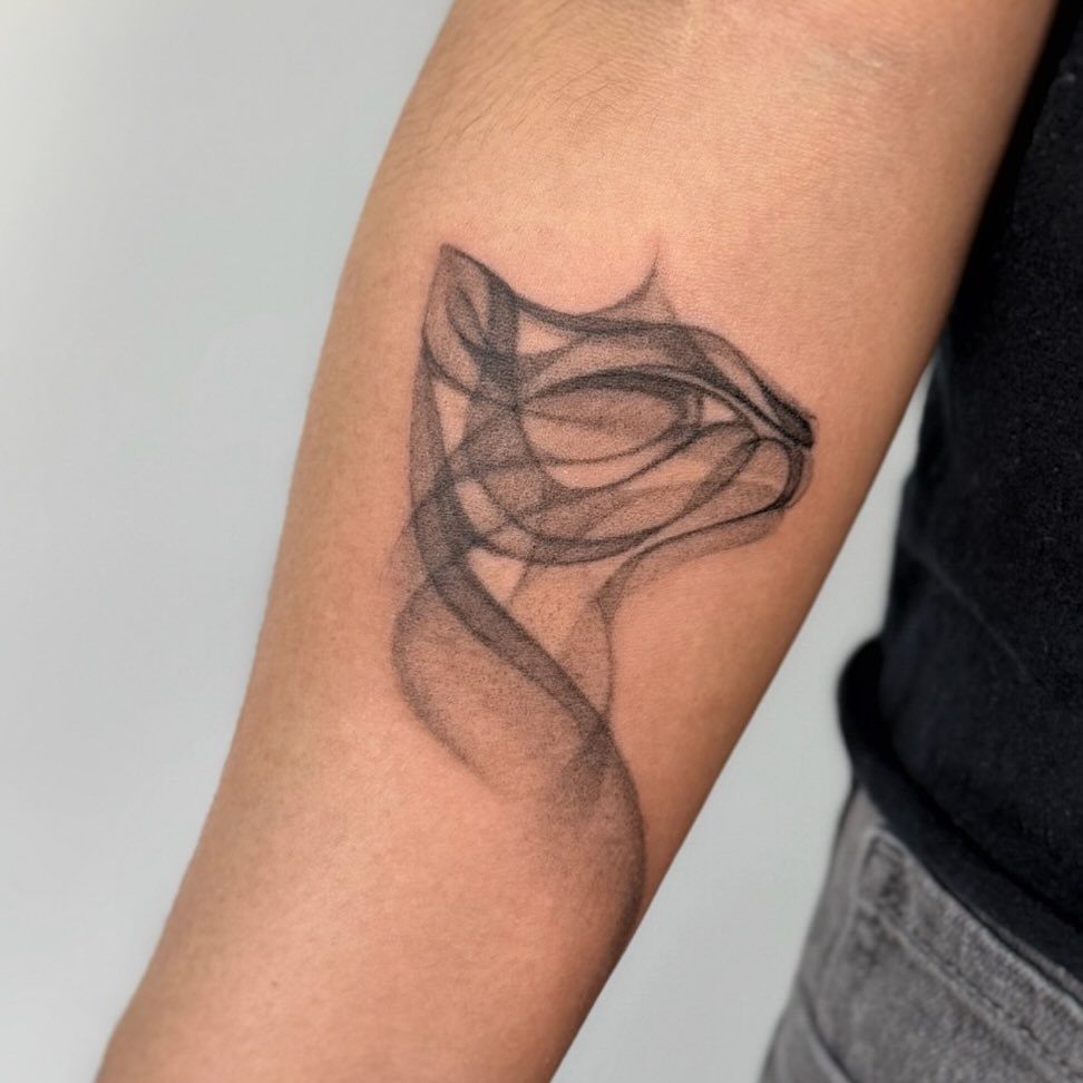 A black ink tattoo of a cat silhouette blending into smoky, flowing lines on a forearm.