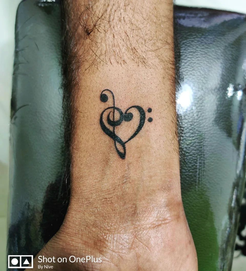12 Easy Tattoo Drawings For Beginners, From Hearts to Tribal Flash 2 A black ink tattoo of a treble clef combined with a heart shape on a wrist.