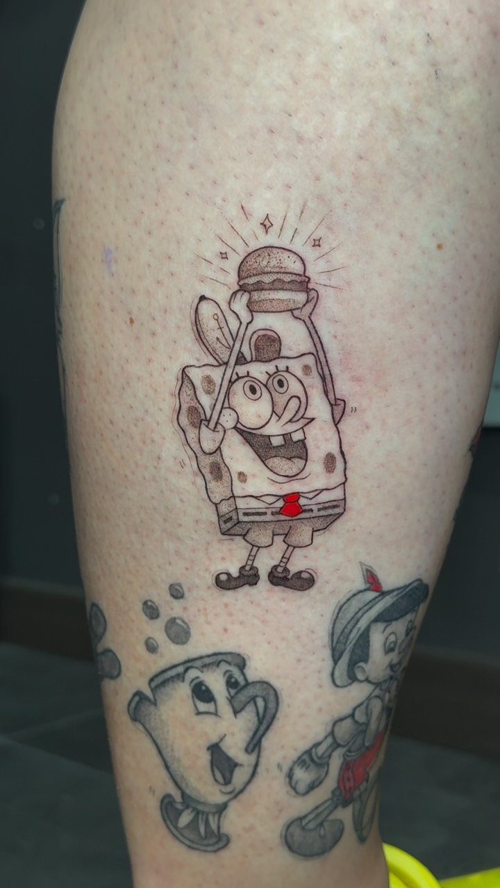 12 Easy Tattoo Drawings For Beginners, From Hearts to Tribal Flash 8 SpongeBob SquarePants tattoo holding a burger on a person's leg with other cartoon characters below.