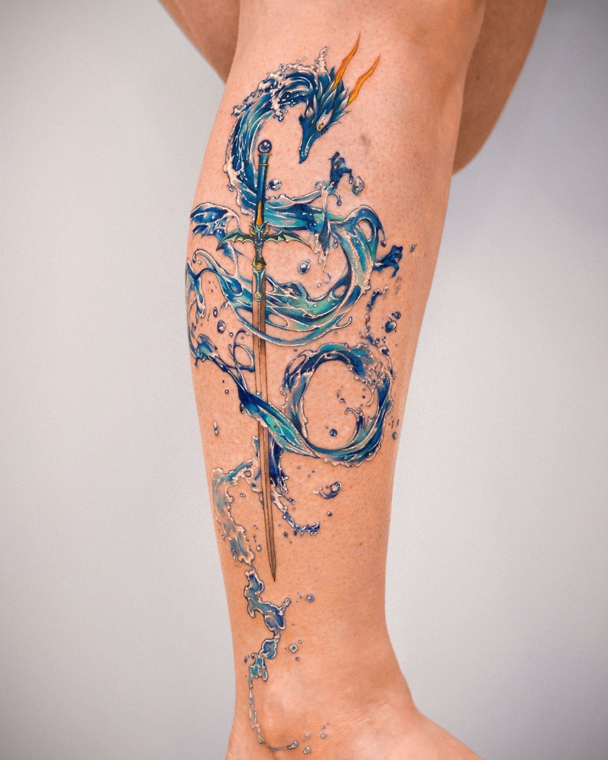 A large blue water and sword tattoo wrapping around a person's lower leg.