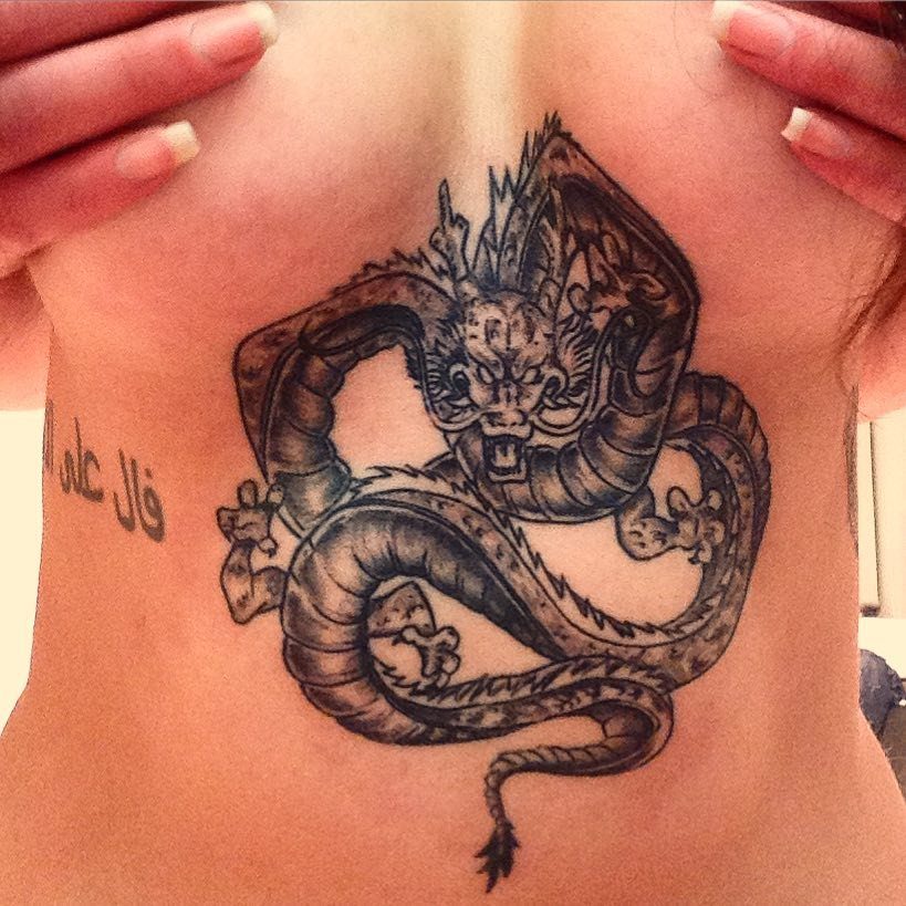 A detailed black and grey dragon tattoo centered on a person's sternum.