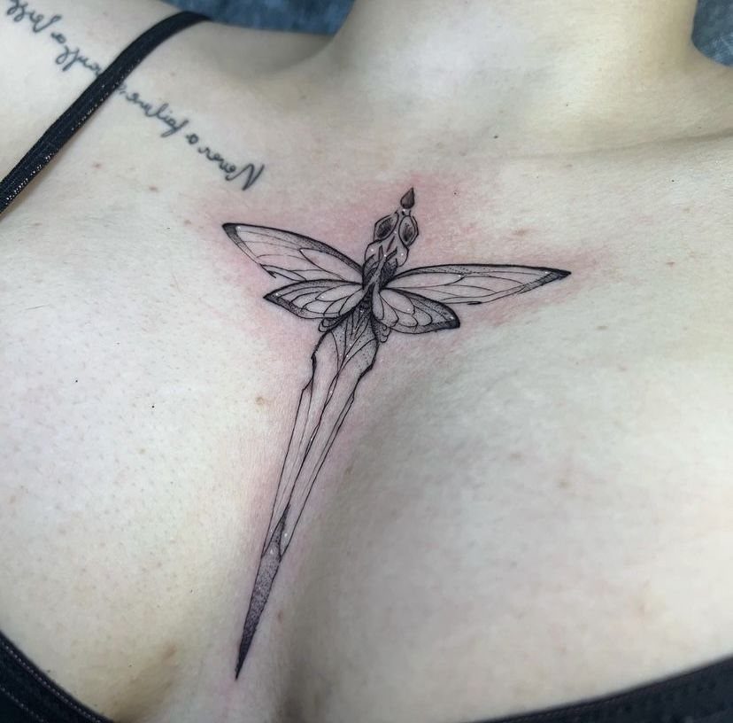 A dragonfly tattoo with a long dagger-shaped body on a person's sternum.