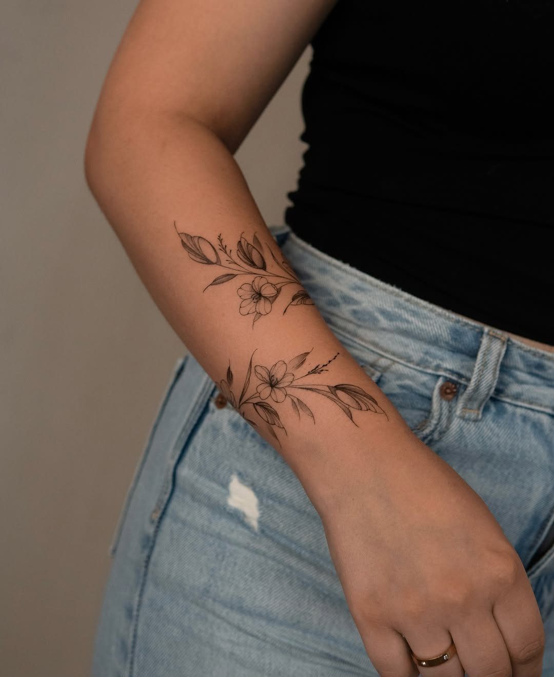 5 Fine Line Flower Vine Tattoo Ideas for Placement and Flow 1 Two delicate fine line floral vine tattoos on a person's forearm with small flowers and leaves.