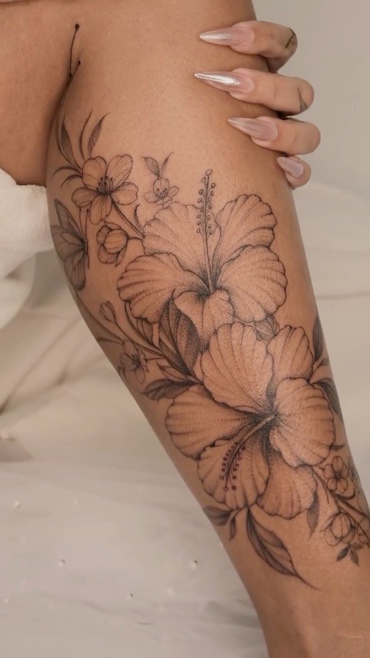 13 Large Flower Tattoo Ideas for Your Next Big Bloom 10 Large black and grey hibiscus flower tattoos covering a person's leg.