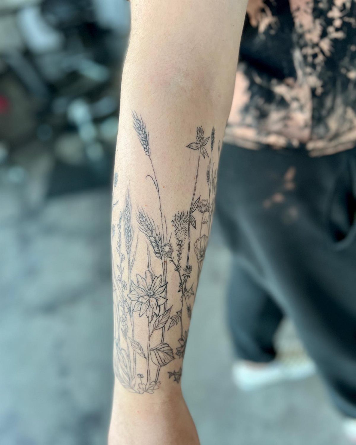 13 Large Flower Tattoo Ideas for Your Next Big Bloom 13 A fine-line black ink wildflower tattoo covering a person's forearm.