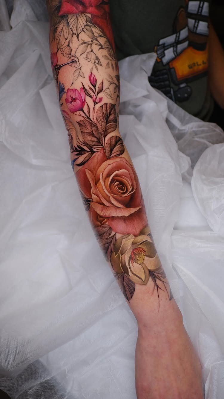 13 Large Flower Tattoo Ideas for Your Next Big Bloom 1 A large realistic rose tattoo in peach tones on a person's forearm surrounded by leaves.