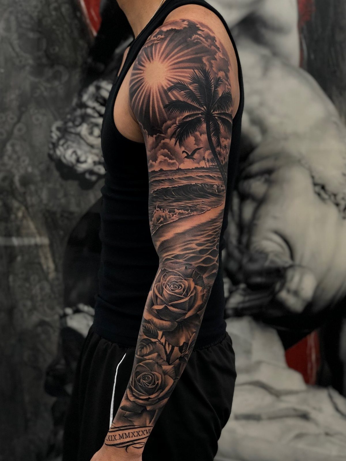 10 Ocean Themed Tattoos: From Fine Line Turtles to Black and Grey Mantas 2 A detailed black and grey sleeve tattoo featuring palm trees, ocean waves, and roses on an arm.