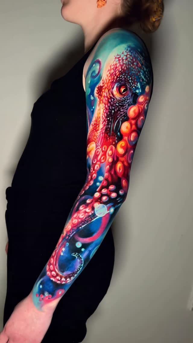 10 Ocean Themed Tattoos: From Fine Line Turtles to Black and Grey Mantas 5 A colorful octopus sleeve tattoo with vibrant red and blue ink on a person's arm.