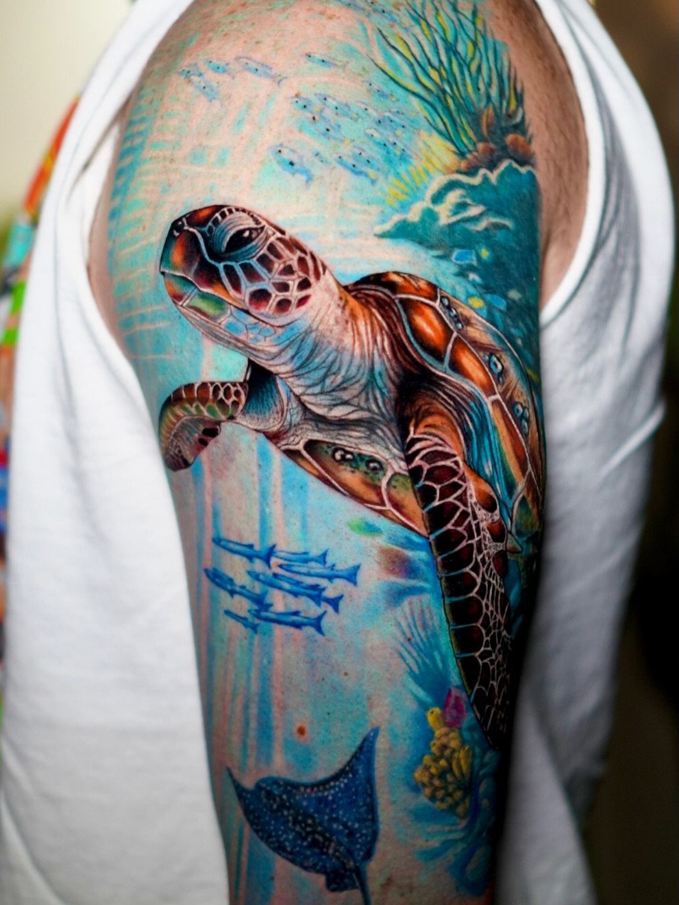 10 Ocean Themed Tattoos: From Fine Line Turtles to Black and Grey Mantas 6 A vibrant sea turtle tattoo on a person's arm surrounded by ocean life.