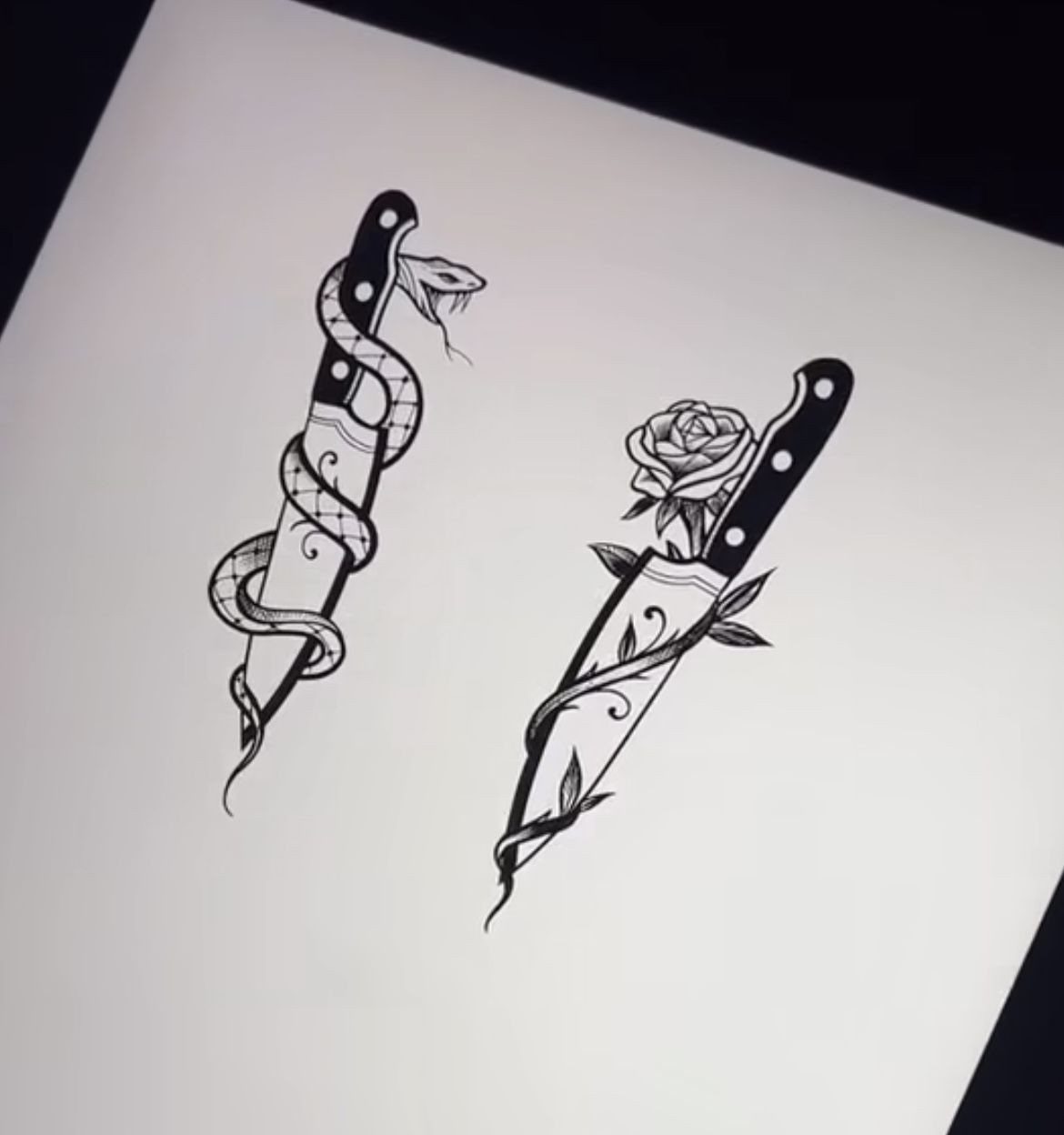 Two black ink tattoo sketches of knives wrapped in a snake and a rose vine.