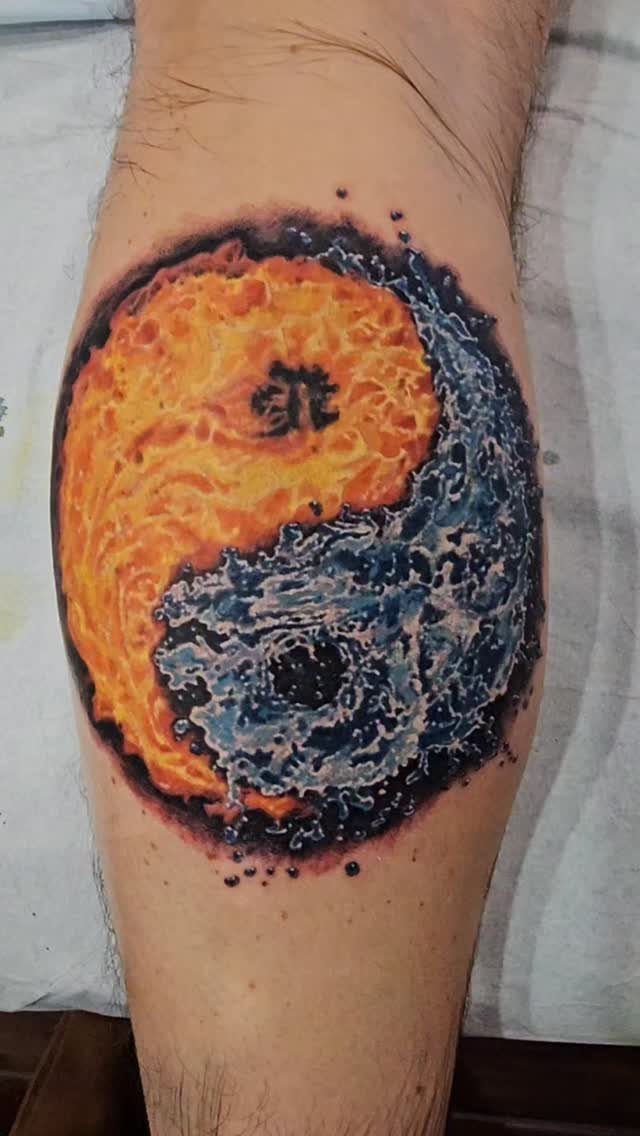 A yin yang tattoo on an arm featuring orange flames and blue water.