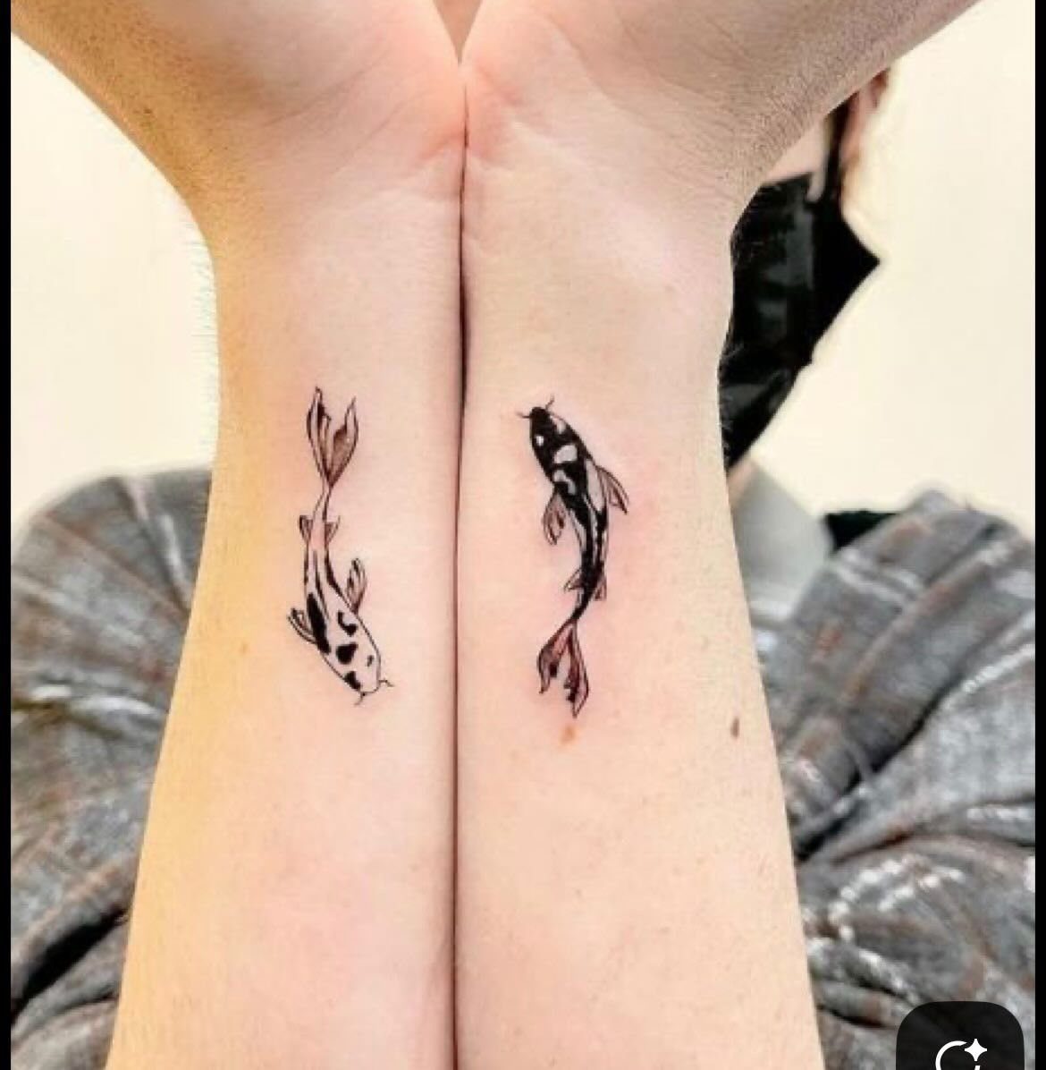 Two small black and white koi fish tattoos on the inner wrists of two people.