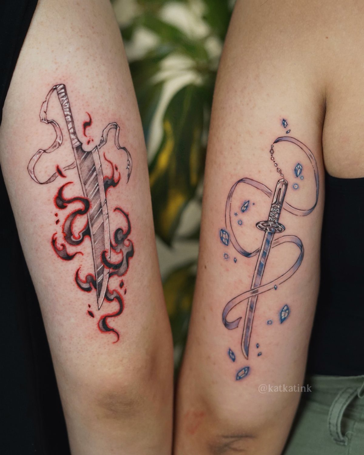 Two arms displaying matching sword tattoos with red flame and blue water elements.