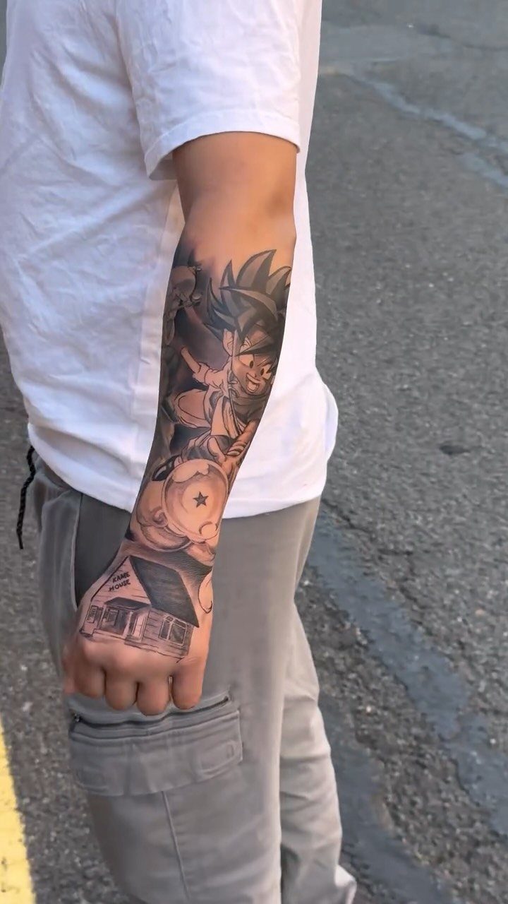 A person's forearm displaying a detailed black and grey anime character tattoo sleeve.