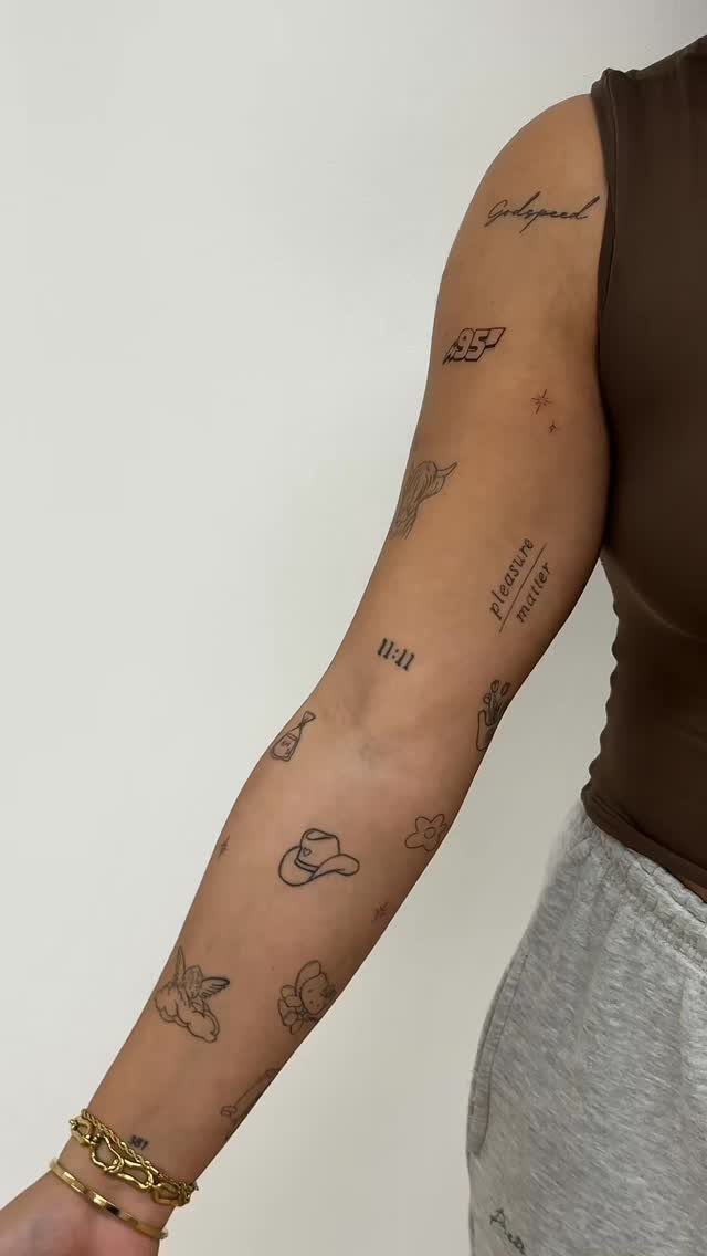 A person's arm decorated with multiple small, individual black ink patchwork style tattoos.