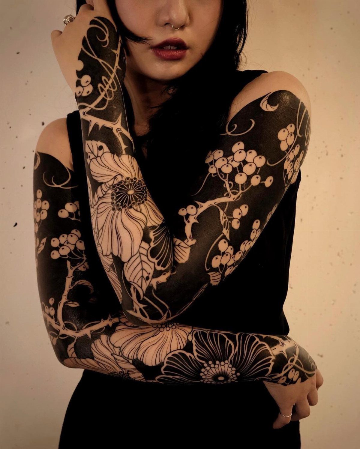 22 Tattoo Pattern Floral Ideas for Arms, Ribs & Full Sleeves 19 A person displaying a large blackwork floral tattoo covering their entire arms with intricate flower patterns.
