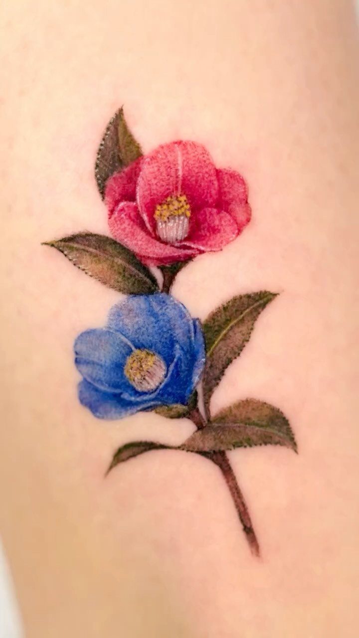 22 Tattoo Pattern Floral Ideas for Arms, Ribs & Full Sleeves 14 Two camellia flower tattoos, one pink and one blue, with green leaves on a stem.