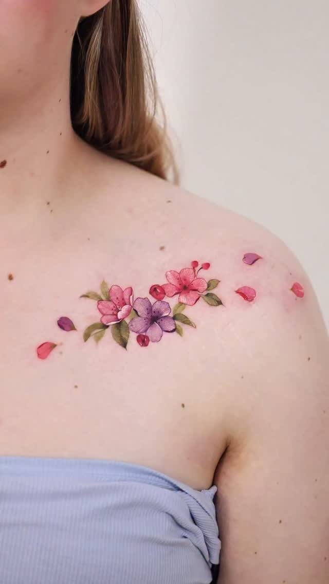 22 Tattoo Pattern Floral Ideas for Arms, Ribs & Full Sleeves 2 Watercolor floral tattoo with pink and purple blossoms on a person's shoulder.