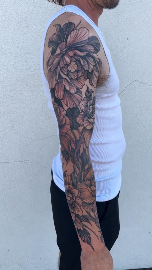 22 Tattoo Pattern Floral Ideas for Arms, Ribs & Full Sleeves 11 A man's arm displaying a large, detailed black and grey floral sleeve tattoo.