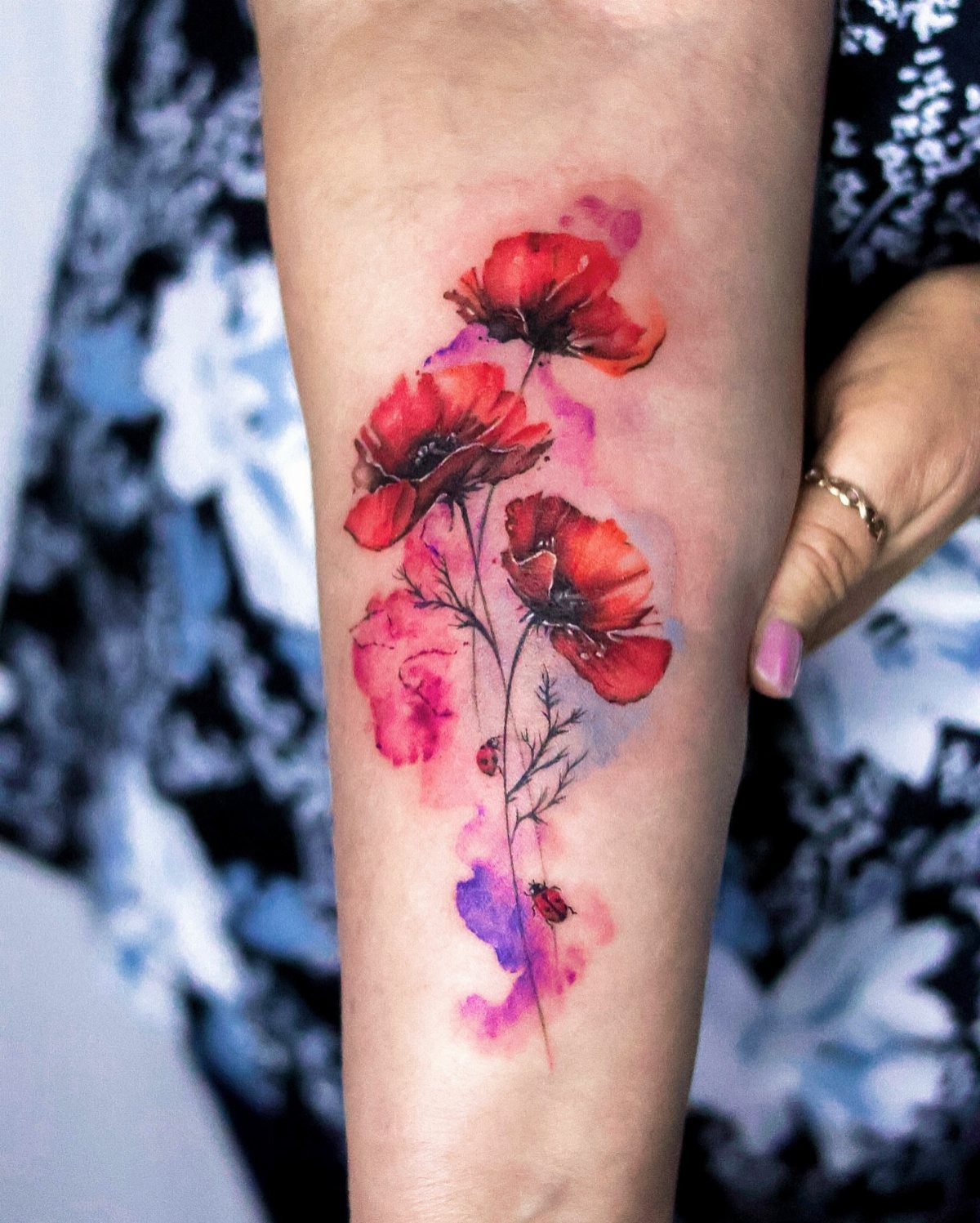 22 Tattoo Pattern Floral Ideas for Arms, Ribs & Full Sleeves 12 Watercolor style red poppy flowers tattooed on a person's forearm with pink and purple accents.