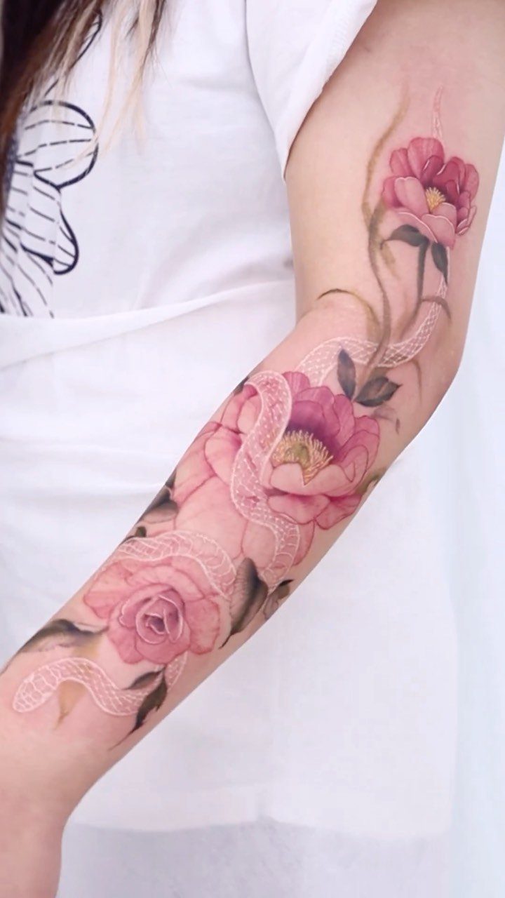 22 Tattoo Pattern Floral Ideas for Arms, Ribs & Full Sleeves 22 A large tattoo of pink peonies and a patterned snake winding around a person's arm.