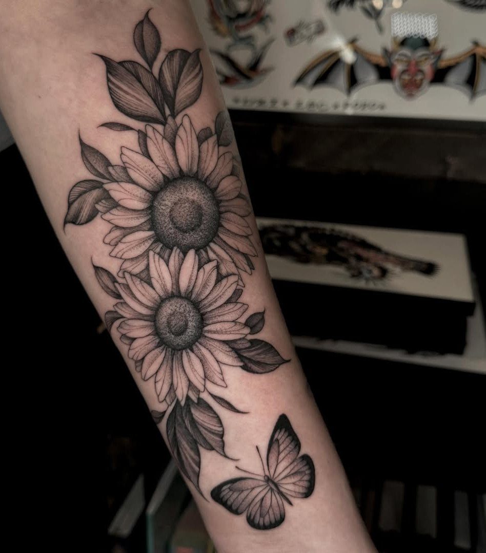 22 Tattoo Pattern Floral Ideas for Arms, Ribs & Full Sleeves 3 Two large sunflower tattoos with leaves and a butterfly on a person's forearm.