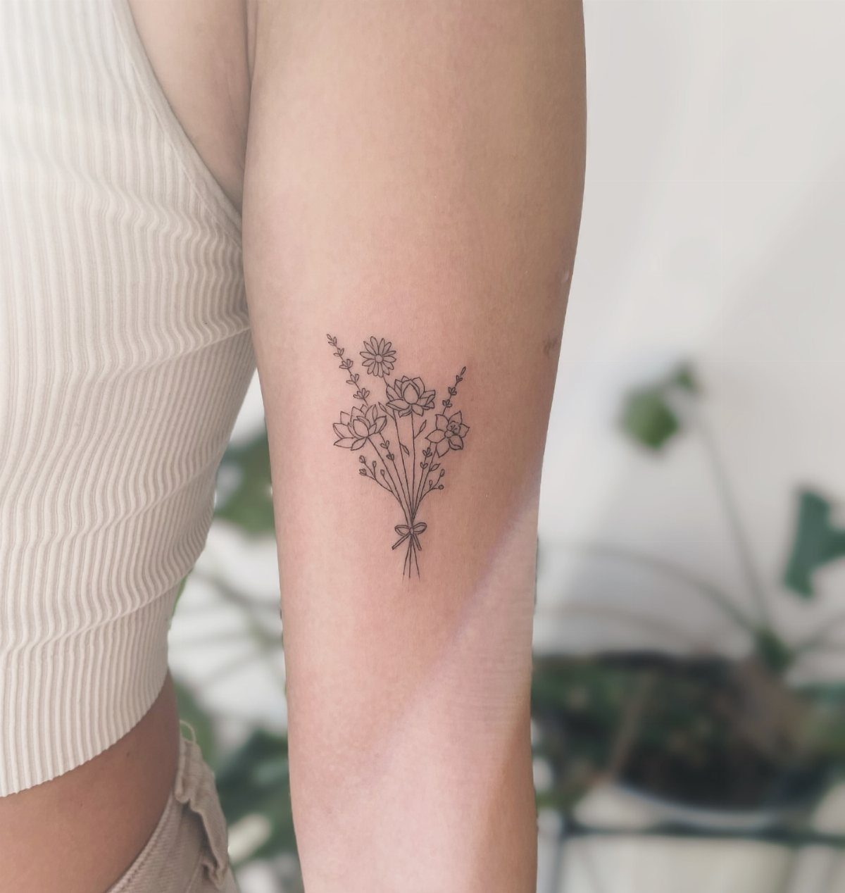 22 Tattoo Pattern Floral Ideas for Arms, Ribs & Full Sleeves 16 A small fine line tattoo of a wildflower bouquet on a person's arm.