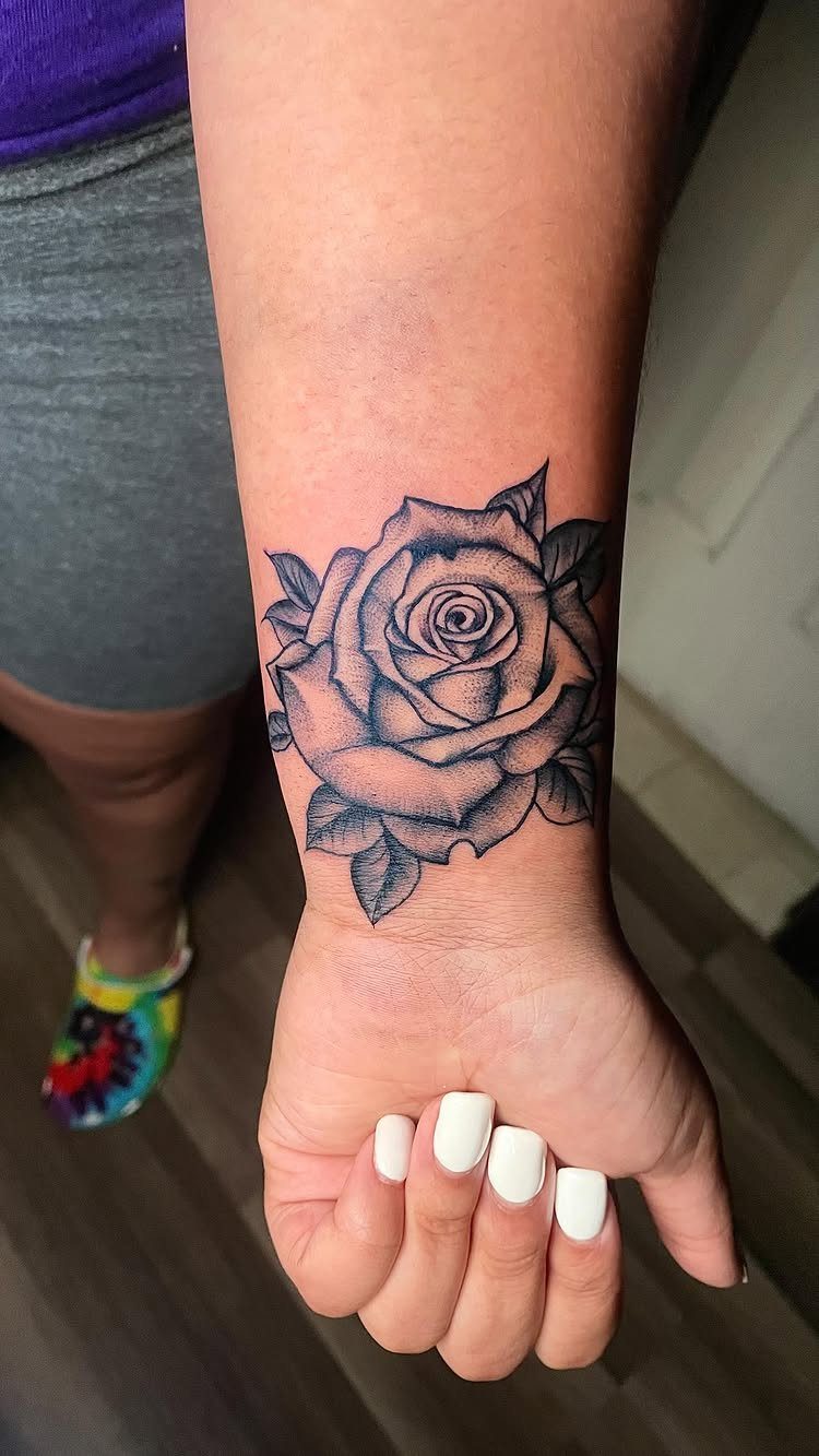 A black and grey rose tattoo prominently displayed on a person's wrist.