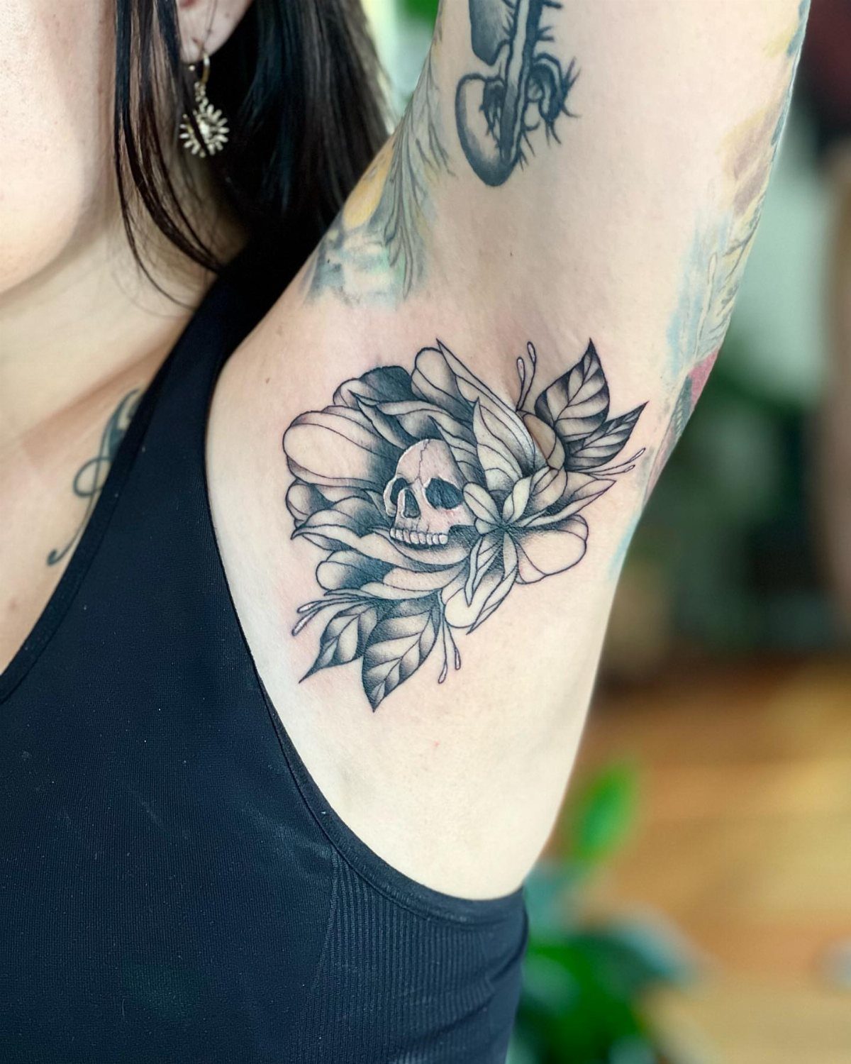 A black and grey rose and skull tattoo placed on a person's underarm.