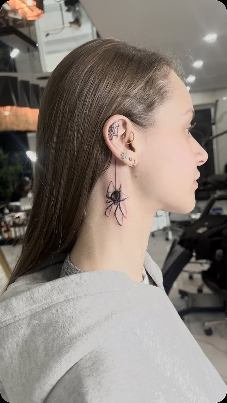 A woman with a small black spider tattoo on the side of her neck.