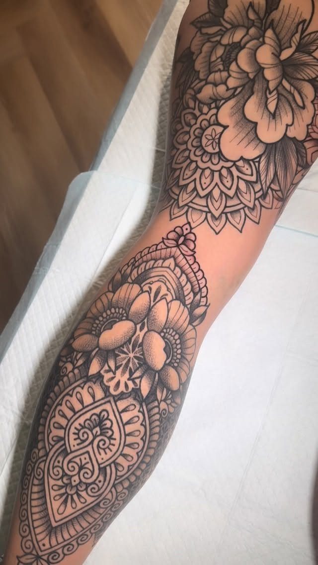 Intricate black ink floral and mandala tattoos covering a person's forearm and upper arm.