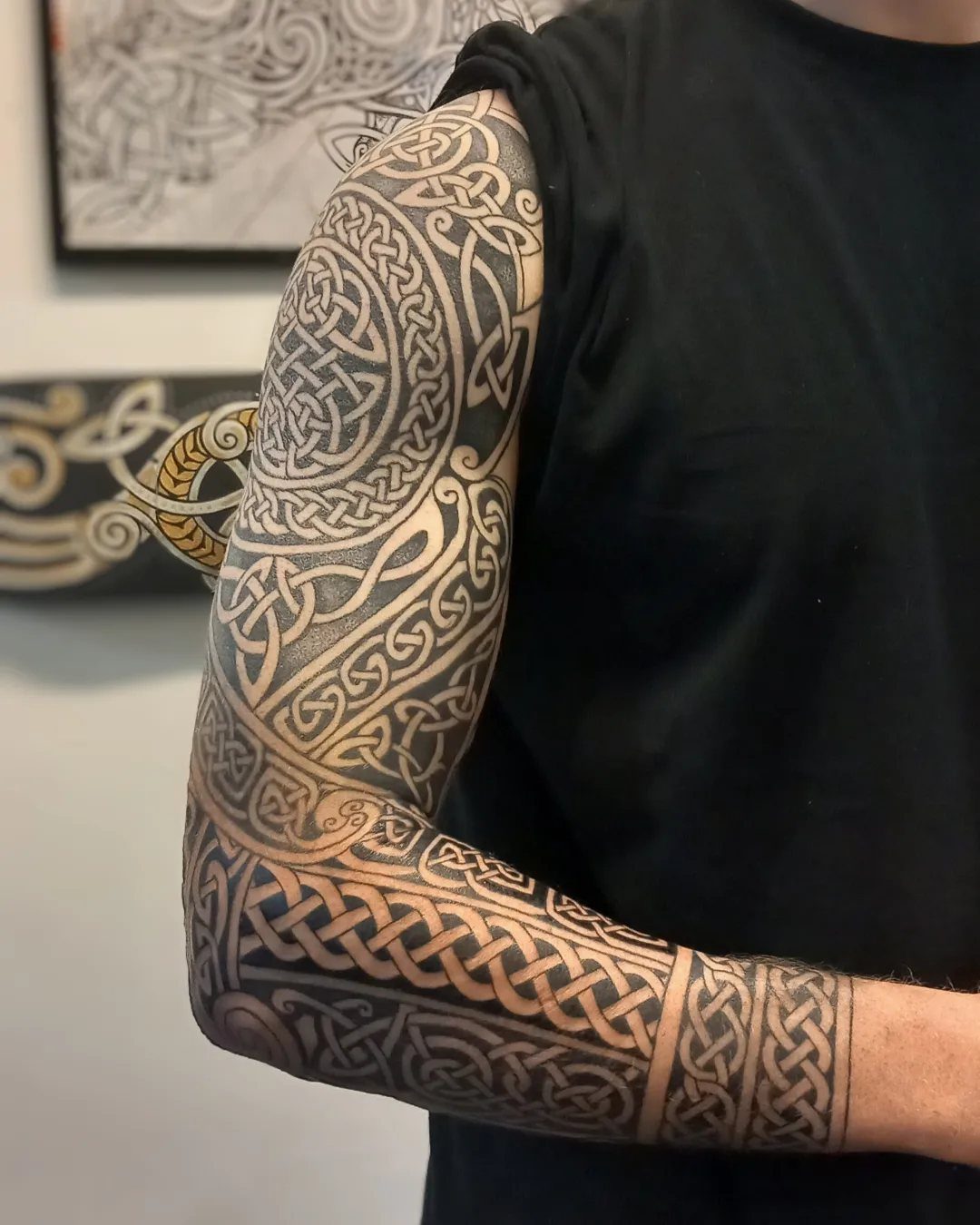 A man's arm featuring a large, detailed black ink Celtic knotwork tattoo.