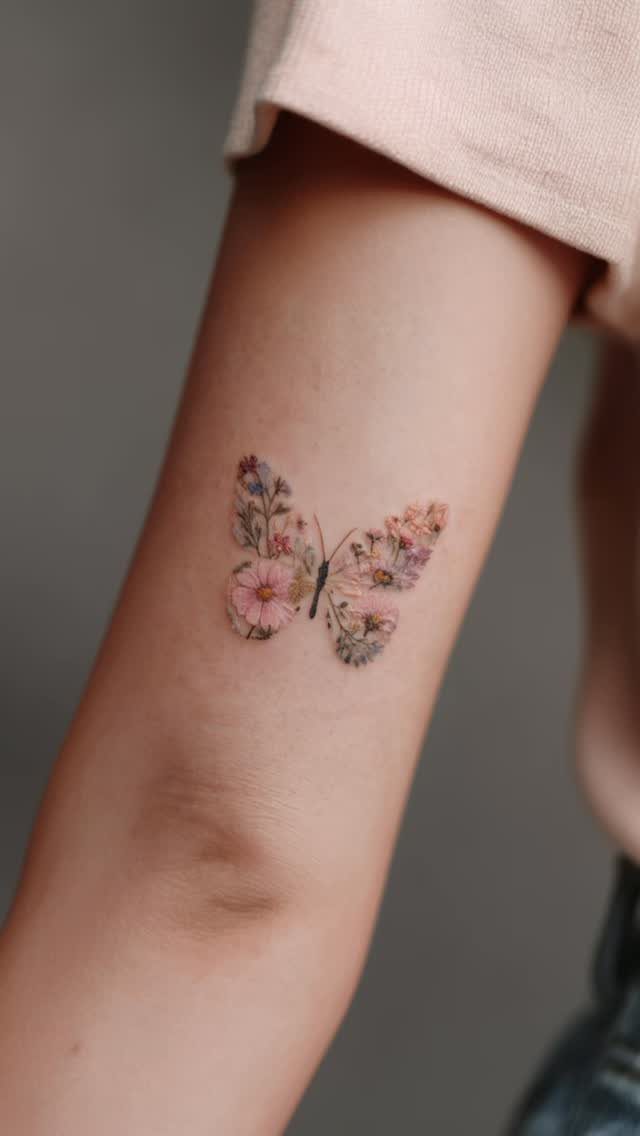 A colorful butterfly tattoo made of small flowers on a person's arm.