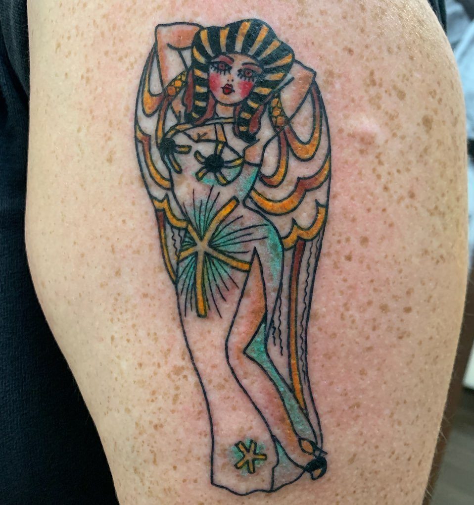 A traditional style tattoo of a winged woman with yellow and black hair on skin.