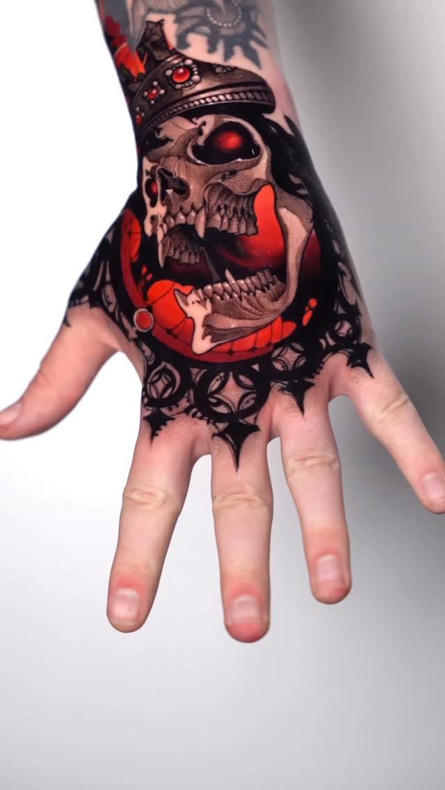 A large black and red skull tattoo covering a person's hand and wrist.