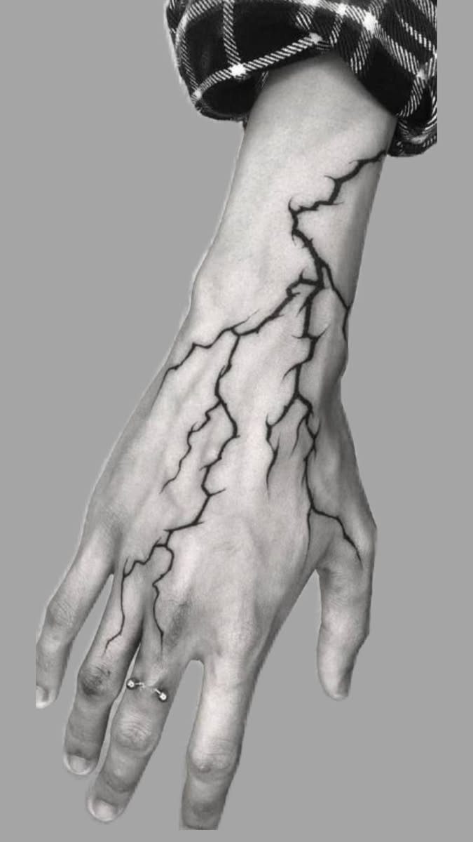 A hand and forearm featuring a large black ink lightning bolt pattern tattoo.