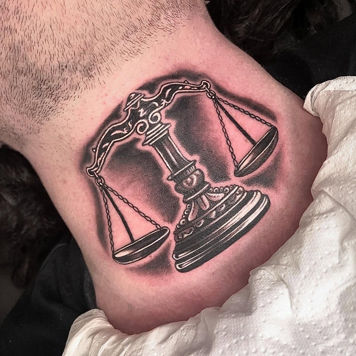 A detailed black and grey tattoo of ornate scales on a person's neck.