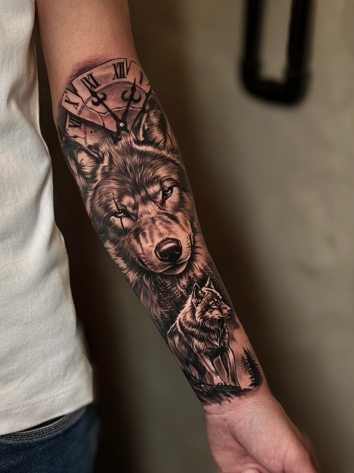 A detailed black and grey wolf tattoo with a clock and forest on a forearm.